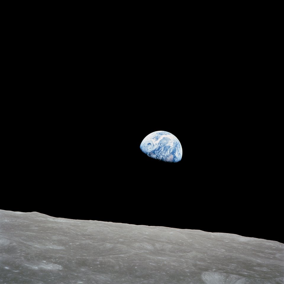 Earthrise: the half-lit blue Earth hanging in black space above the grey lunar horizon.