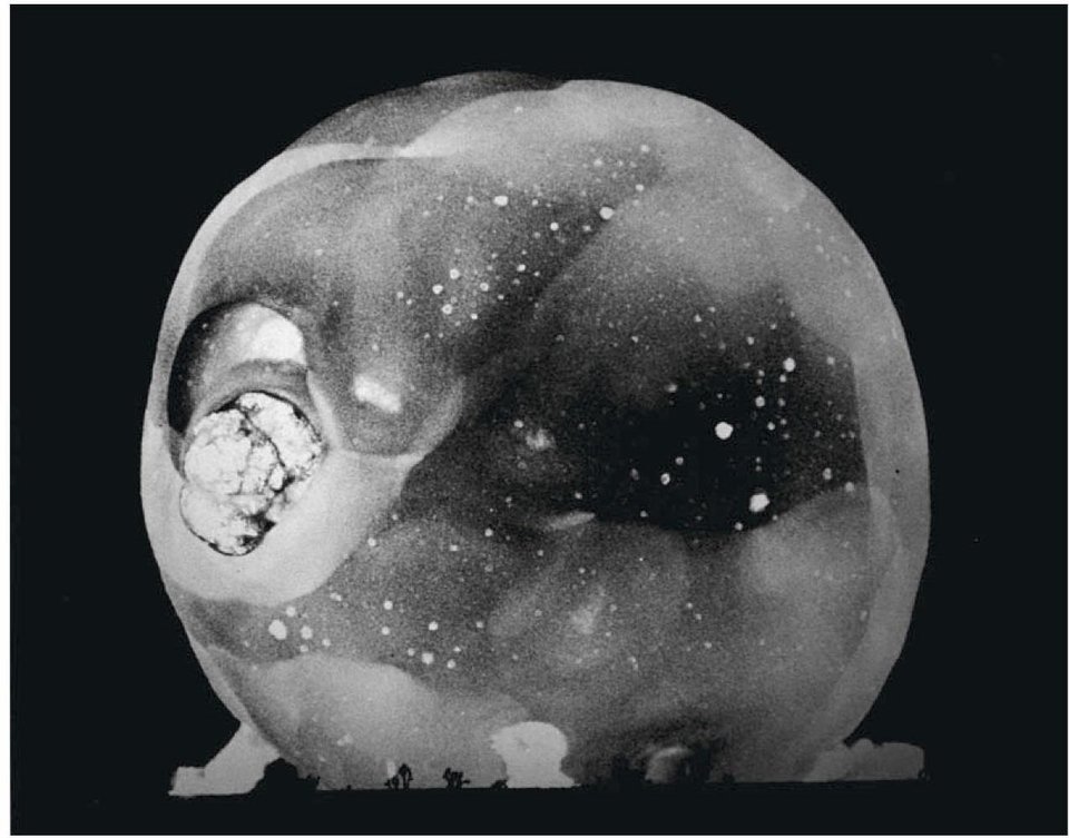 High-speed photograph of an atomic test: a spherical, mottled fireball an instant after detonation, against black.