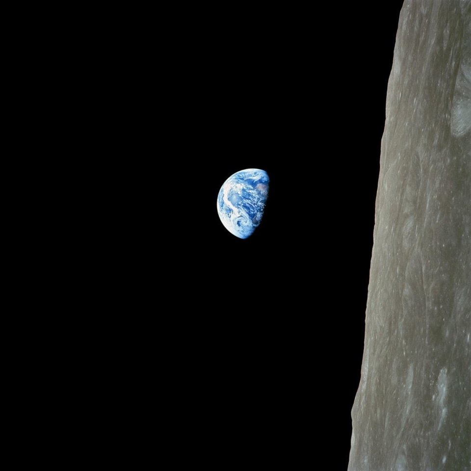 Earthrise: the half-lit blue Earth hanging in black space above the grey lunar horizon.